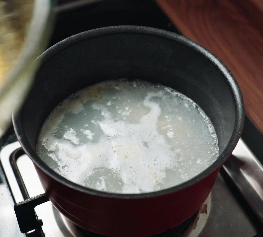 Un bol mélangeur en verre posé sur une casserole deau fumante pour créer un système de bain-marie.