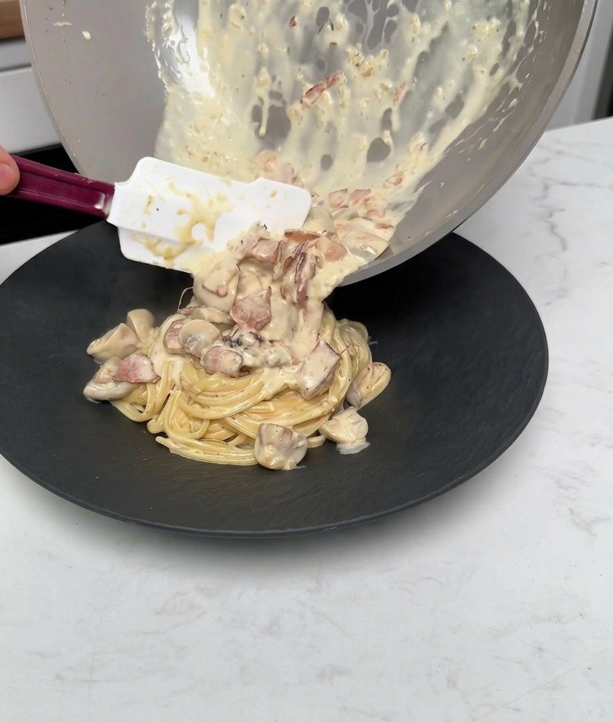 Verser le reste de sauce crémeuse, de champignons et de bacon depuis la poêle sur les pâtes dressées.