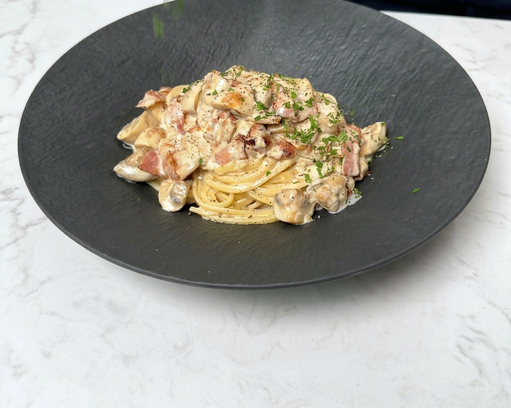 Saupoudrer du persil vert fraîchement haché sur une assiette fumante de linguines crémeuses.
