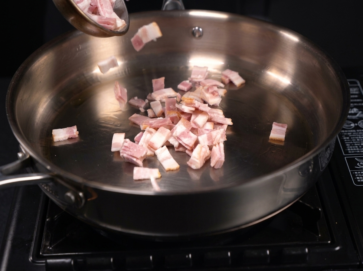 De petits morceaux de viande hachés grésillant et libérant leur gras dans une poêle en acier inoxydable.