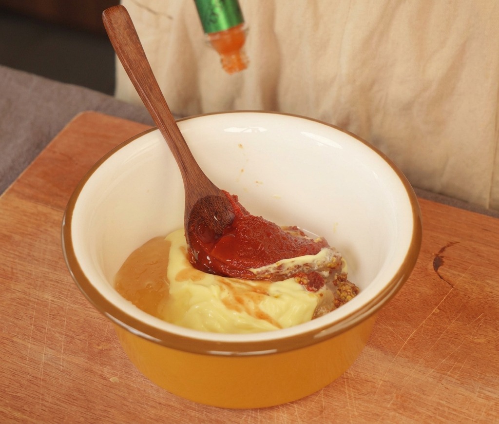 Sauce piquante versée dans un bol jaune contenant de la mayonnaise et de la moutarde.