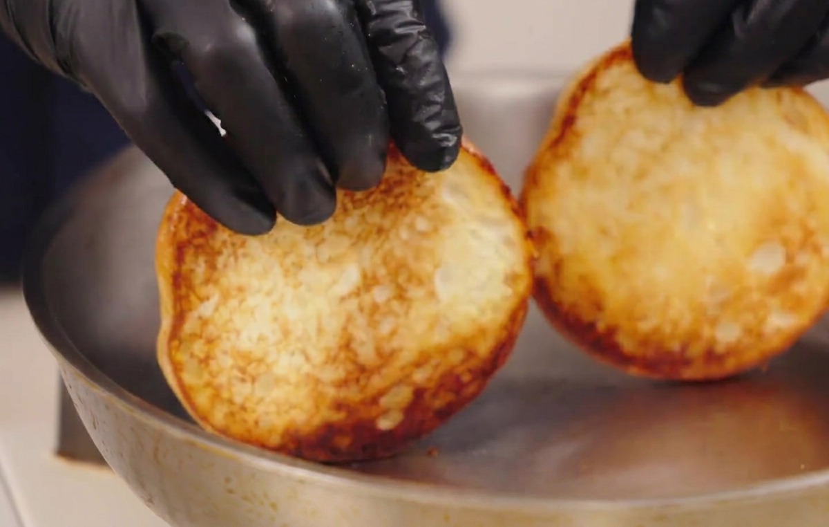 Mains soulevant deux pains toastés montrant une surface bien dorée et caramélisée.