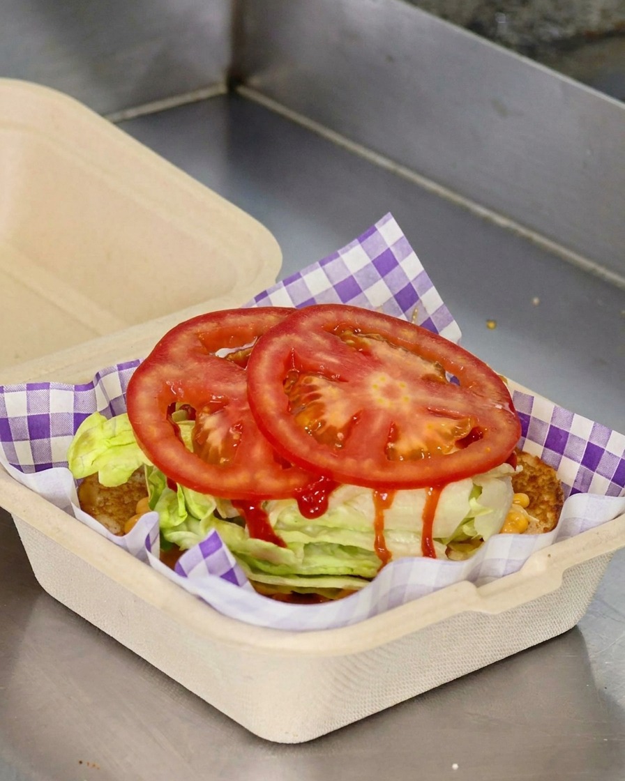 Deux rondelles de tomate fraîche posées sur de la laitue dans un emballage à burger.
