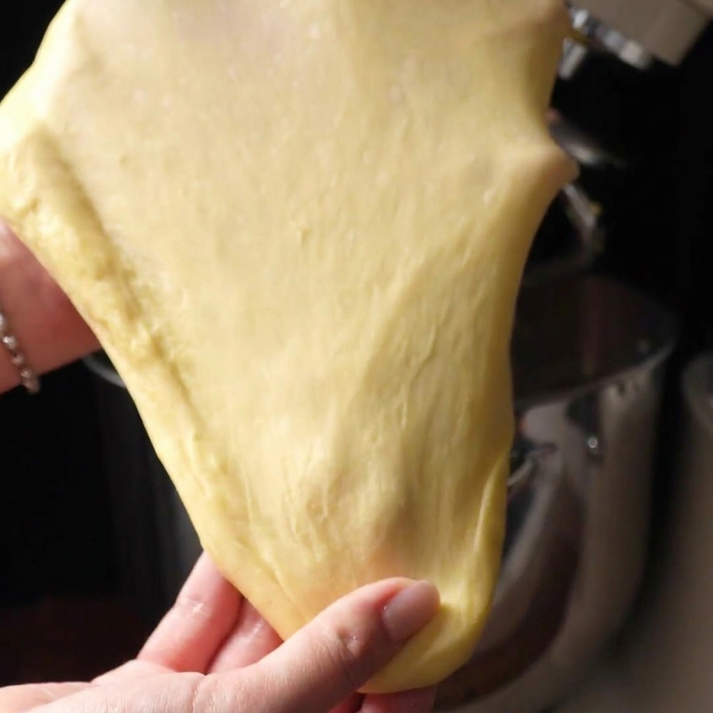 Deux mains étirant une pâte lisse pour former une membrane très fine et translucide.