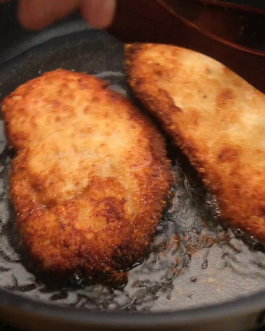 Un morceau de poulet frit croustillant retiré de la poêle avec une spatule.