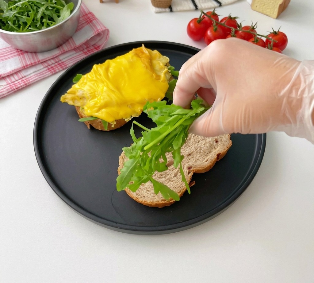 Pose de feuilles de roquette fraîche sur une tranche de pain grillé.
