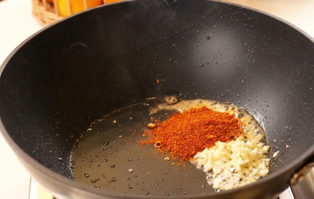 Ail haché et piment en poudre dans de lhuile chaude au fond dun wok noir.