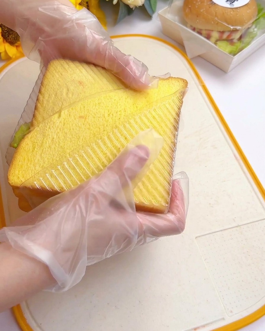 Mains insérant le sandwich dans un moule en plastique triangulaire.