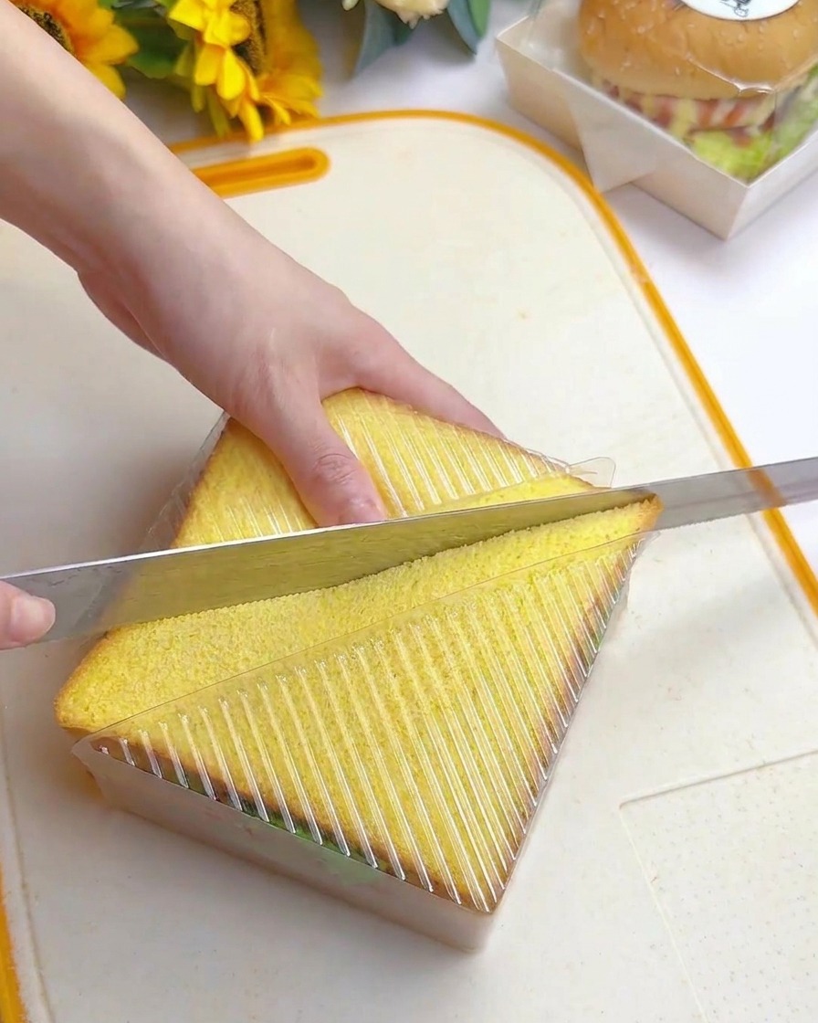 Couteau dentelé coupant le sandwich en deux en suivant le guide du moule.