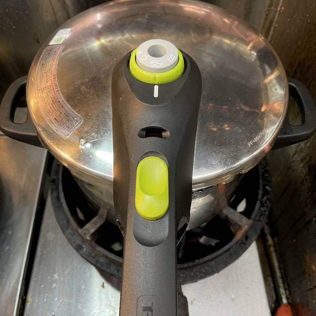 Un autocuiseur en inox avec son couvercle verrouillé sur une plaque de cuisson active.