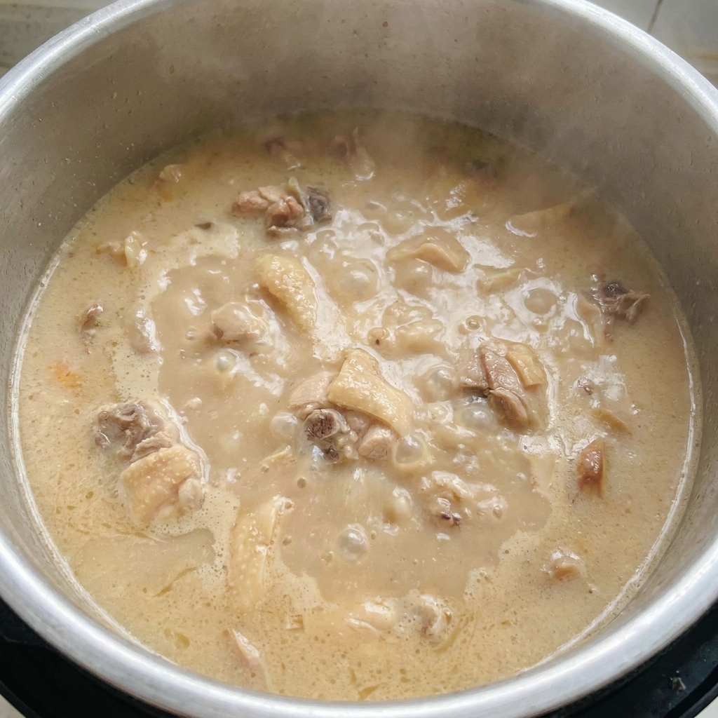Une marmite de bouillon tonkotsu épais et blanc laiteux bouillant vigoureusement.