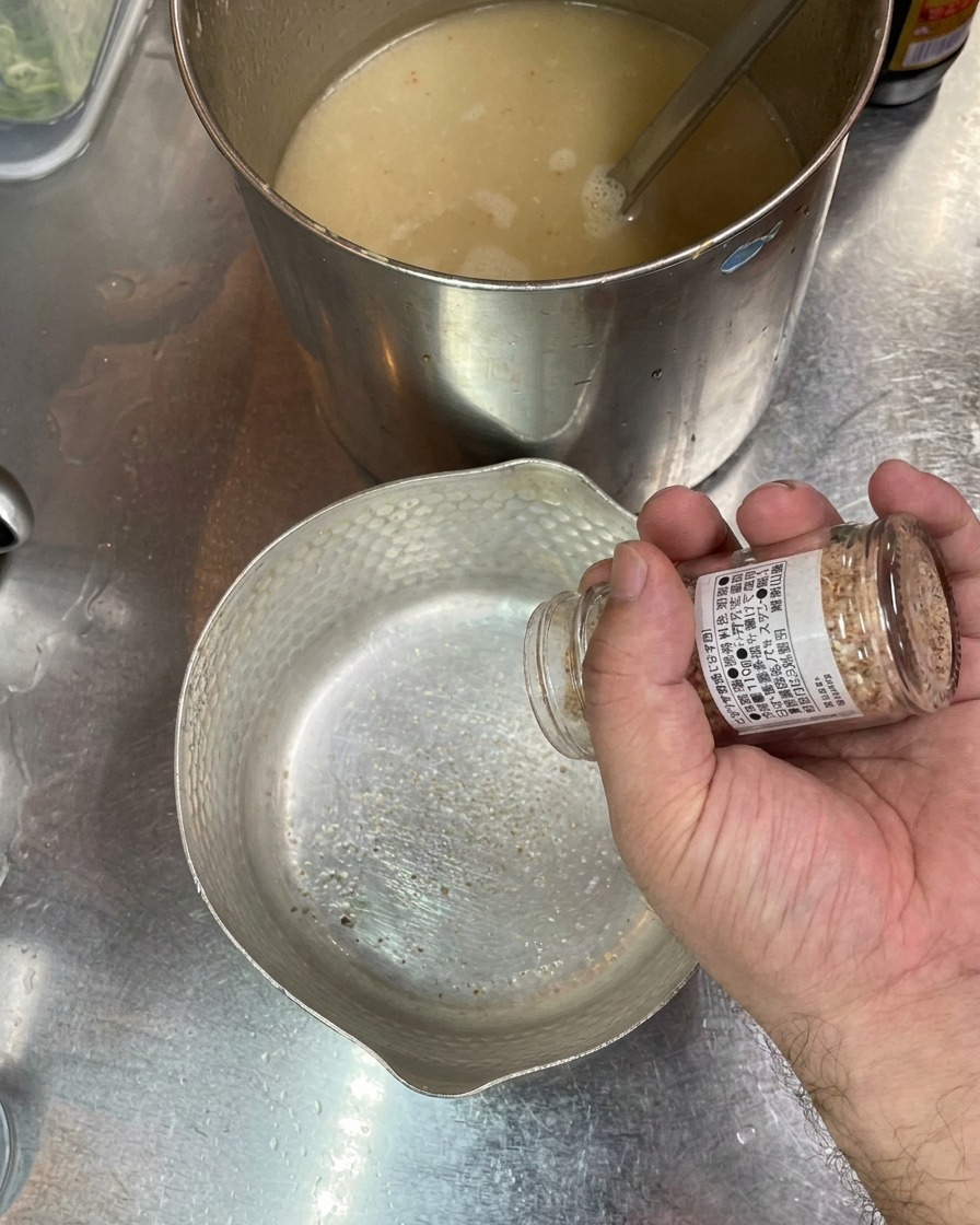 Main versant du sel depuis un bocal dans un bol vide, bouillon en arrière-plan.