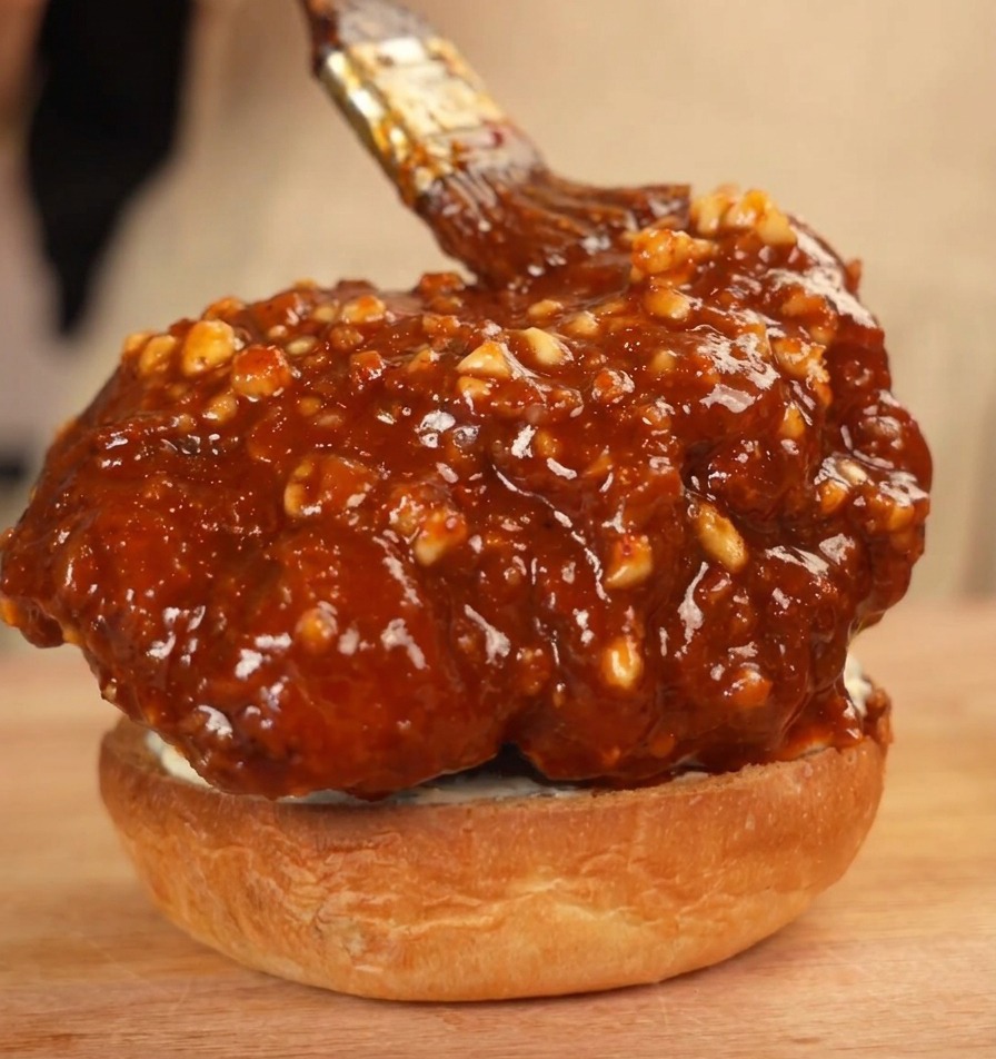 Poulet frit en sauce sur un pain à burger, badigeonné dun surplus de sauce.