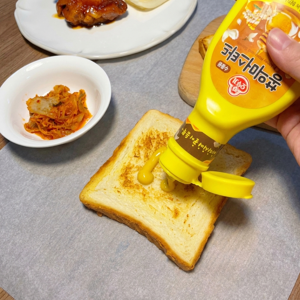 Moutarde jaune appliquée en zigzag sur une tranche de pain de mie bien dorée.