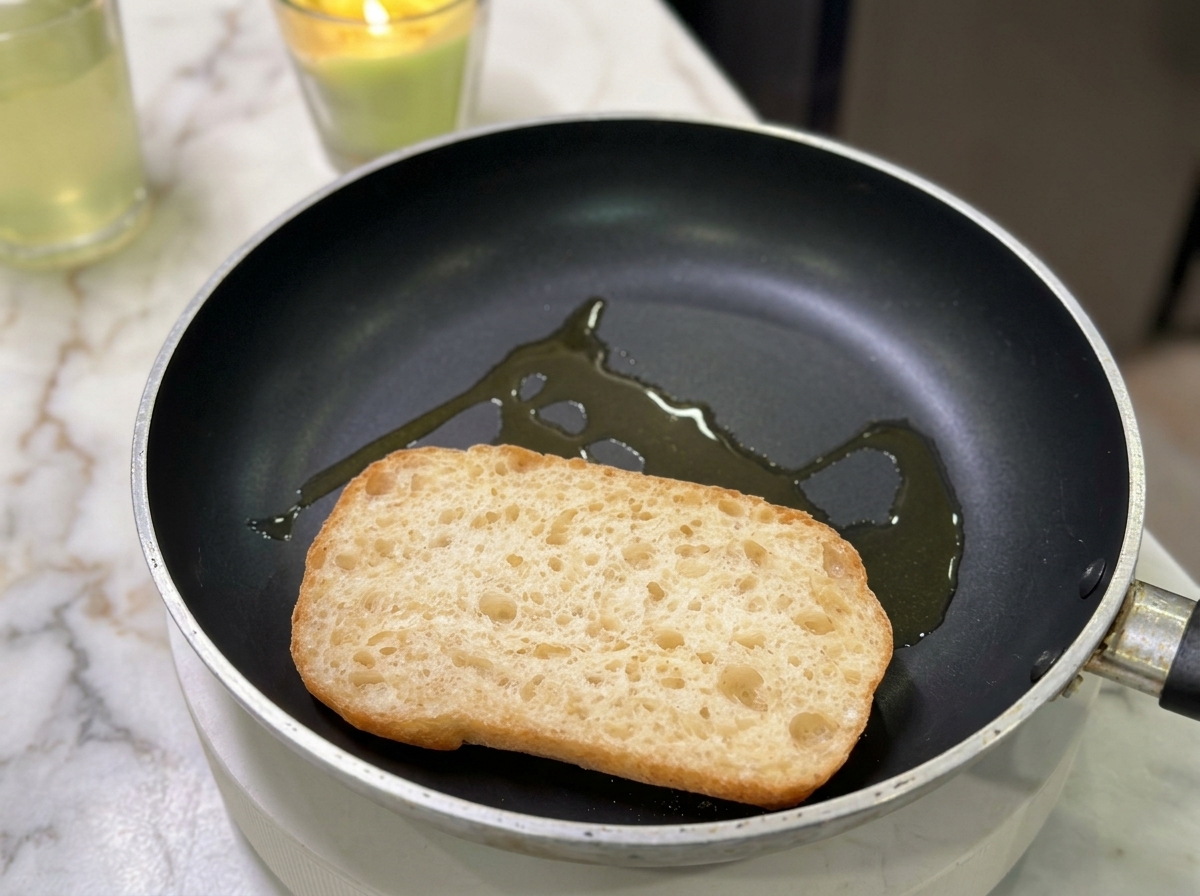 Une moitié de ciabatta grillant dans une poêle avec un filet dhuile.
