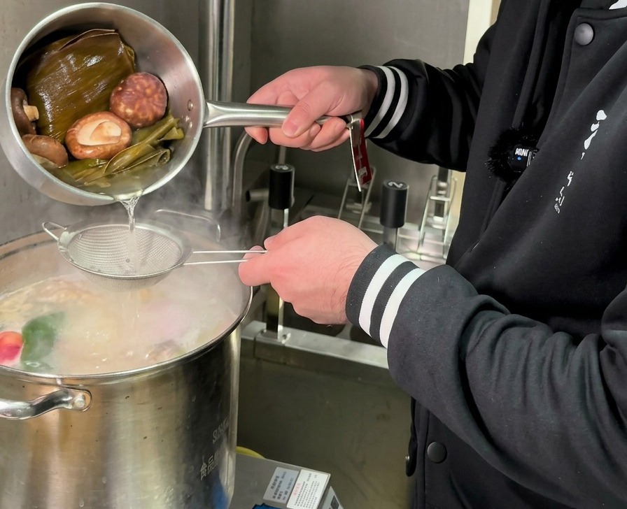 Verser une infusion dorée de champignons et de kombu à travers une passoire dans une grande marmite de bouillon bouillant.