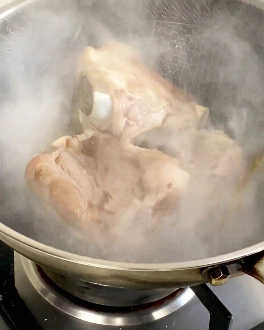 Épais nuage de vapeur blanche séchappant dun wok après lajout de vin de cuisine sur les os de porc.