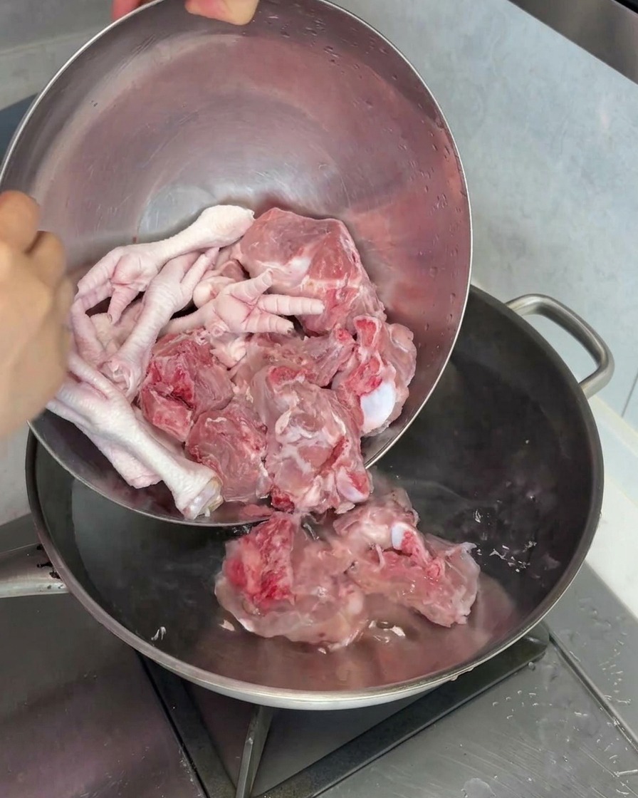 Os à moelle de porc crus et pattes de poulet plongés dans une marmite deau pour être blanchis.