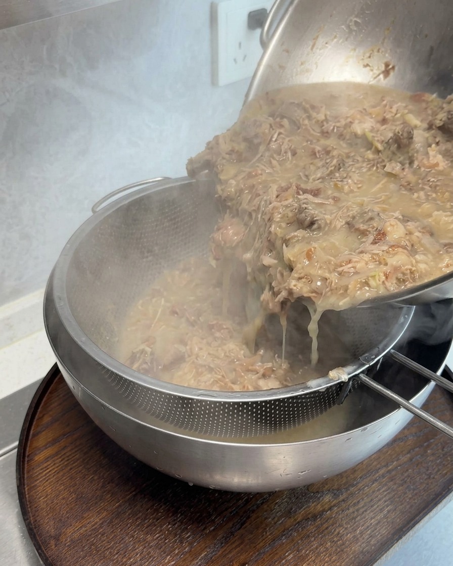 Bouillon dos épais et concentré versé à travers une passoire à mailles fines pour enlever les morceaux de viande.