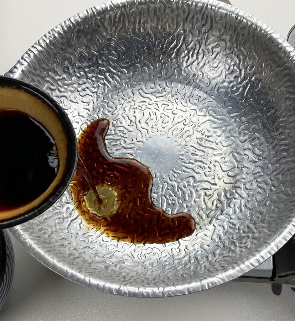 De la sauce soja foncée est versée depuis un petit bol à lintérieur jaune dans une casserole contenant le miso et le sucre.