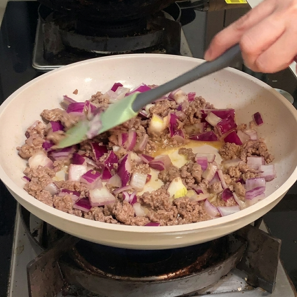 Dés doignon rouge violet et blanc mélangés à du bœuf haché doré dans une poêle.