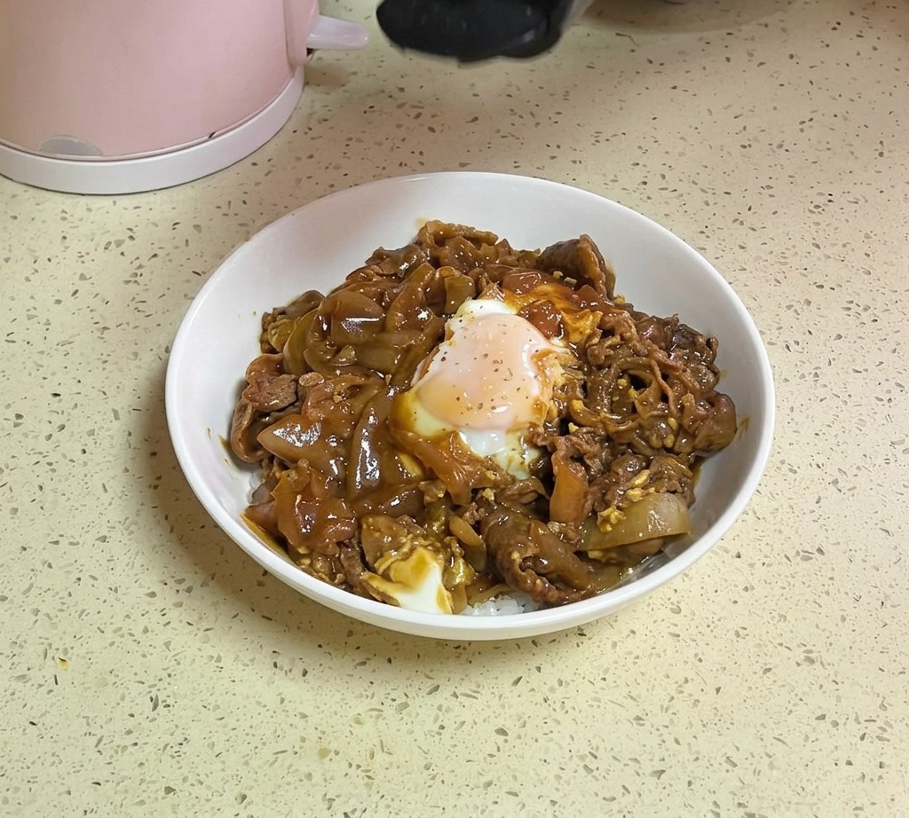 Une main saupoudrant des graines de sésame blanc et des éclats de persil séché depuis un flacon sur un bol de riz au bœuf et à lœuf terminé.