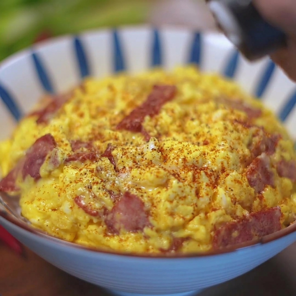 Poivre noir fraîchement moulu par-dessus un bol dœufs brouillés au bacon sur un lit de riz.