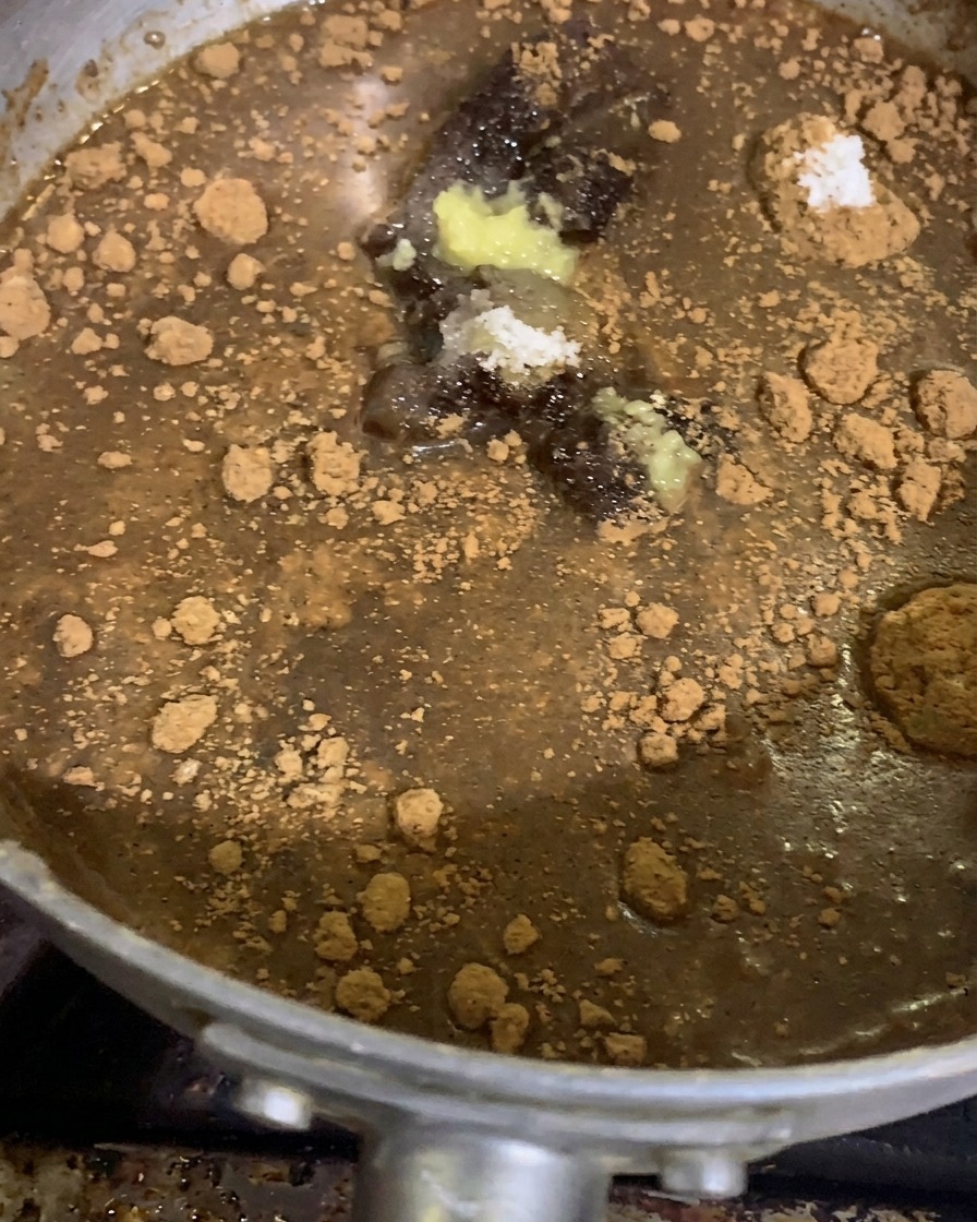 Des tas dépices moulues, de poudres dassaisonnement, dail et de pâte de gingembre posés sur une base de sauce miso épaisse dans une casserole en argent avant la cuisson.