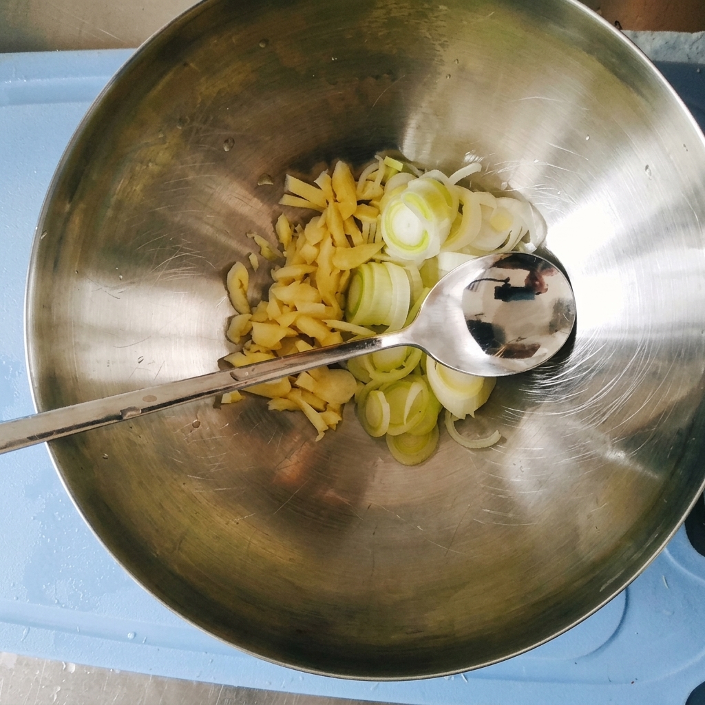 De lail finement haché et des oignons verts émincés dans un grand bol en acier inoxydable avec une cuillère en métal.