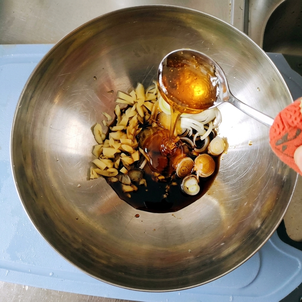 Du sirop de maïs épais et doré versé dune cuillère en argent dans la marinade à lintérieur du bol en métal.