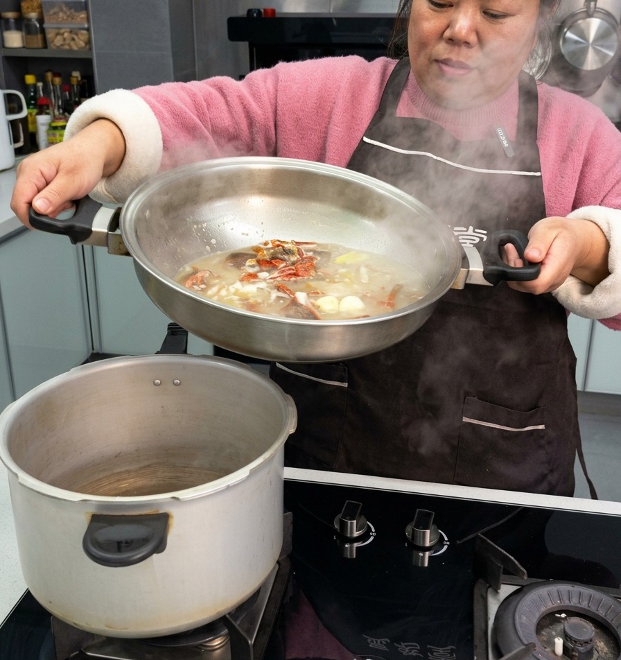 Une personne versant un bouillon riche avec des travers de porc, de lail et des piments depuis une poêle vers la cuve dun autocuiseur.