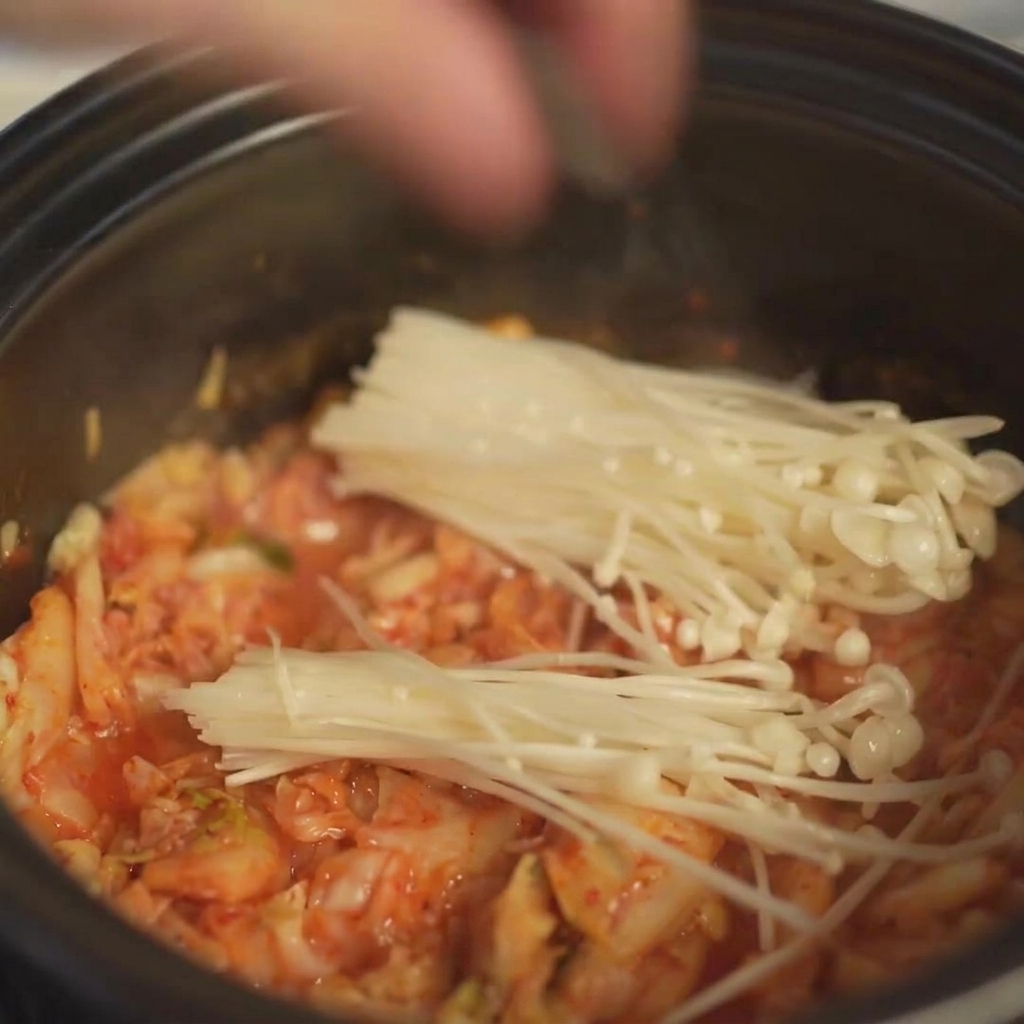 Disposition dun bouquet de champignons enoki frais dans la marmite au-dessus du kimchi.