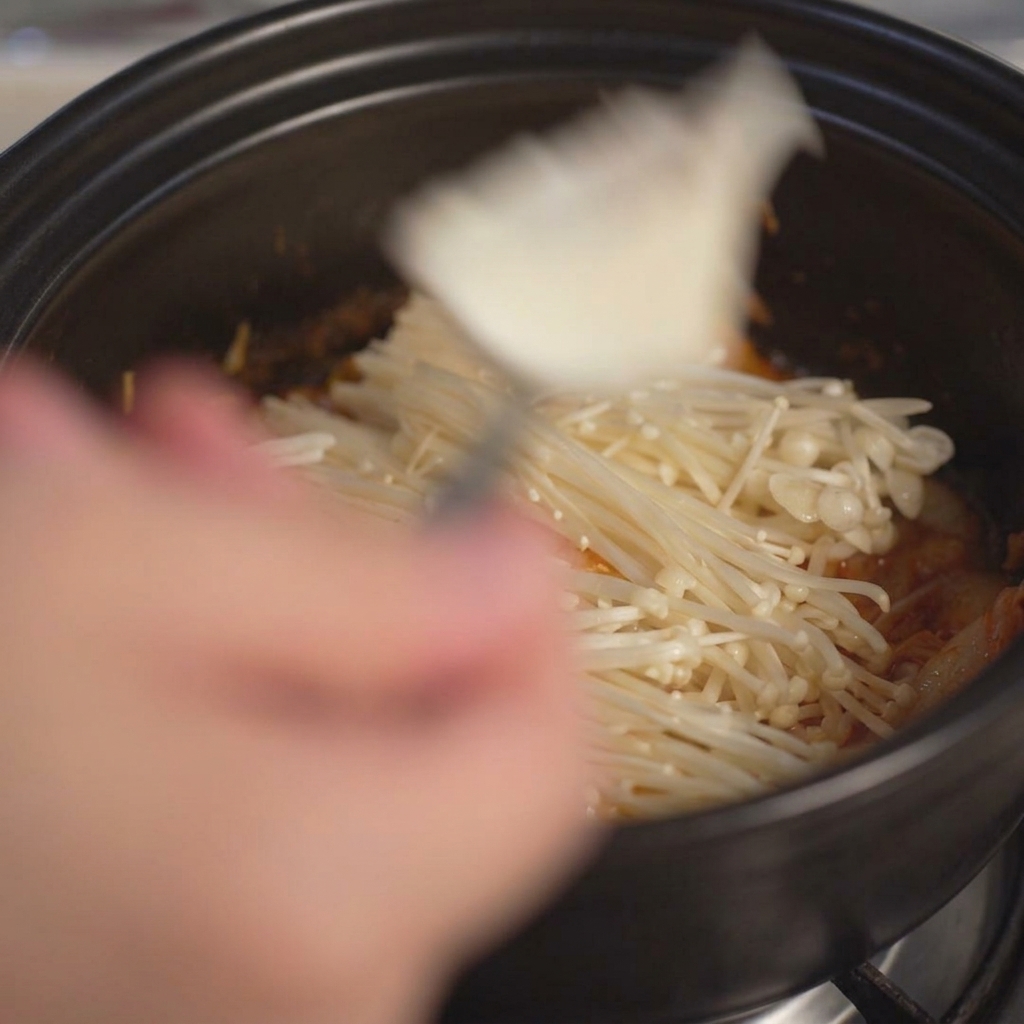Ajout de gros morceaux de tofu blanc soyeux dans la marmite à laide dune cuillère.