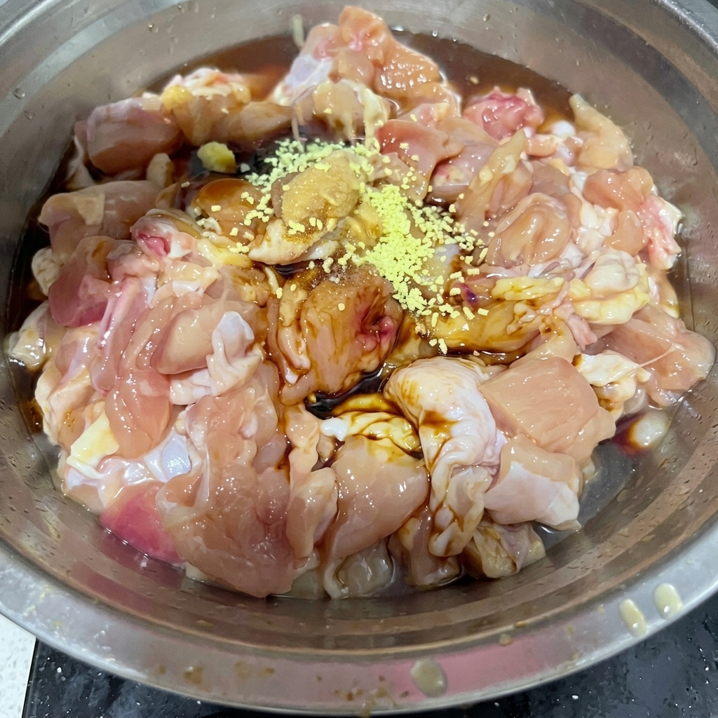 Bouillon de poulet en poudre jaune et sel blanc saupoudrés sur les morceaux de poulet cru dans un bol métallique.