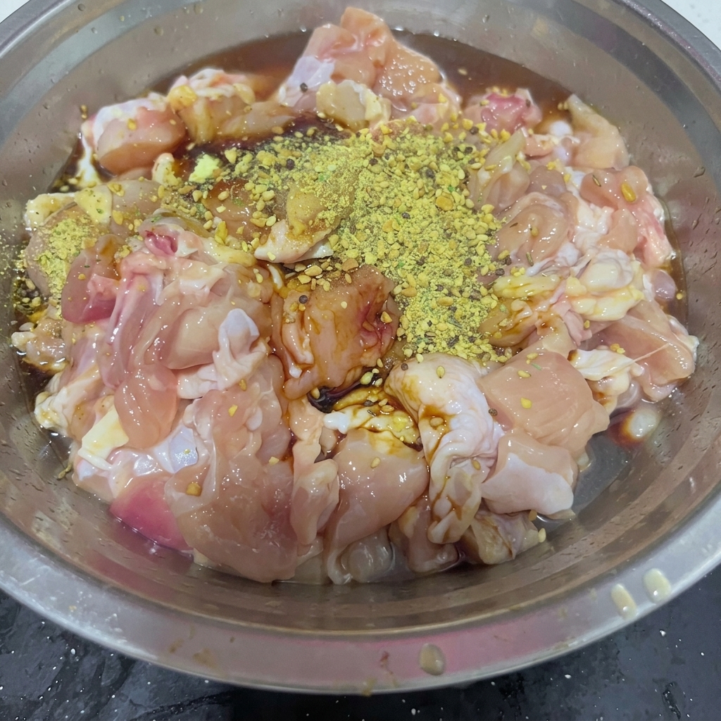 Sucre blanc granulé saupoudré sur le mélange de hauts de cuisses de poulet assaisonnés dans un bol en acier inoxydable.