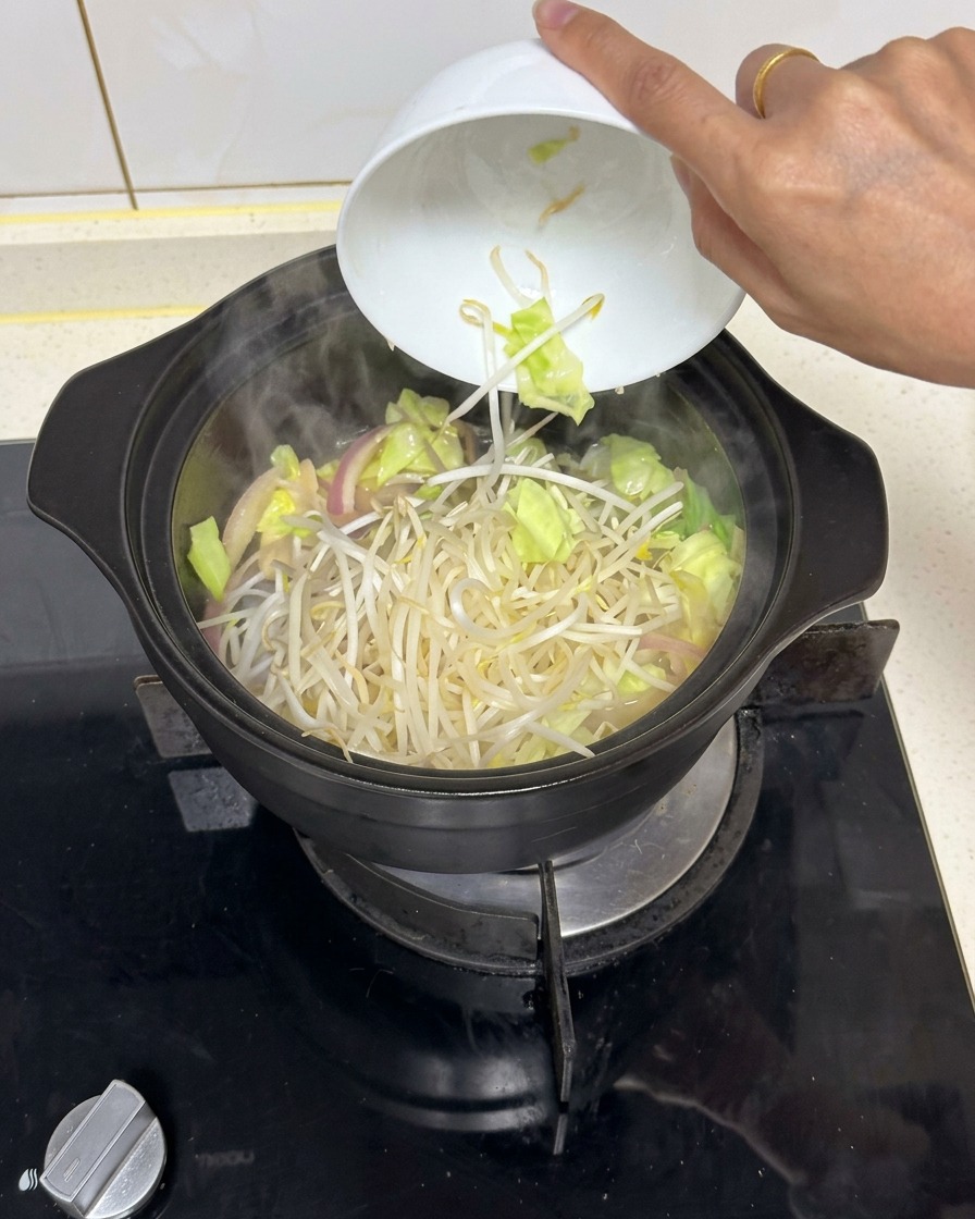 Une poignée de pousses de haricots fraîches versée dun bol en céramique blanc dans une marmite noire fumante de légumes sautés.