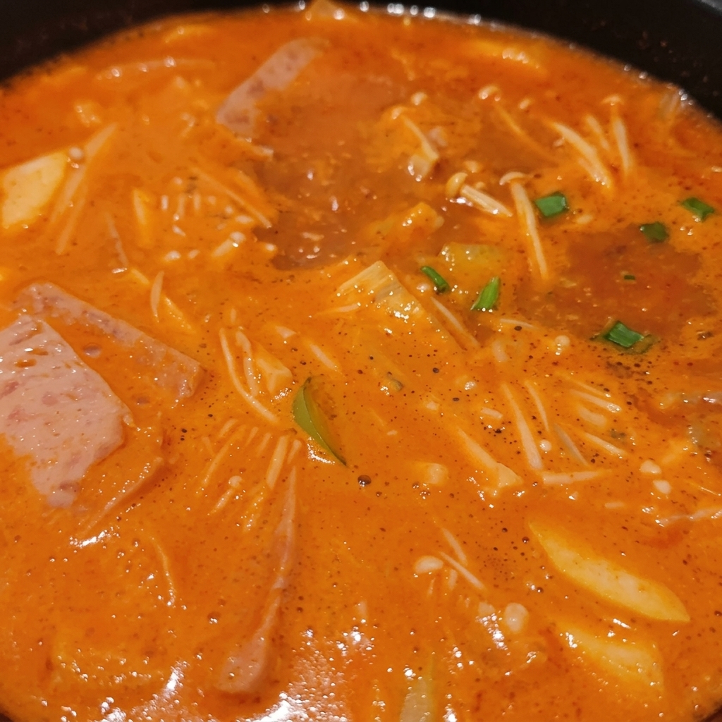 Ragoût coréen bouillonnant rempli denoki, de lamelles de viande, doignons verts et de tofu dans un bouillon riche.