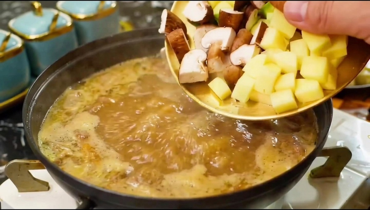 Champignons émincés et morceaux de légumes glissant dune assiette vers une marmite de bouillon chaud assaisonné.