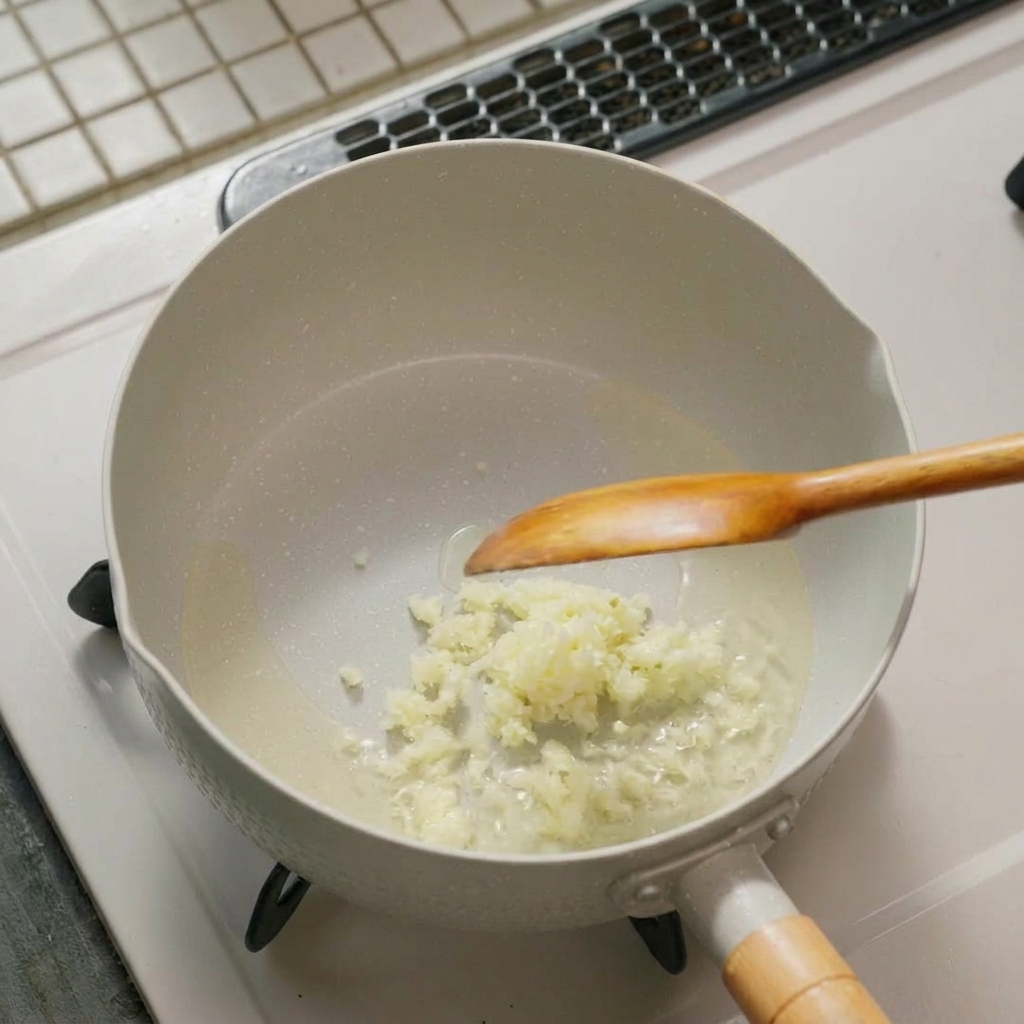 Ail haché et oignons verts grésillant dans lhuile au fond dune poêle avec une spatule en bois.