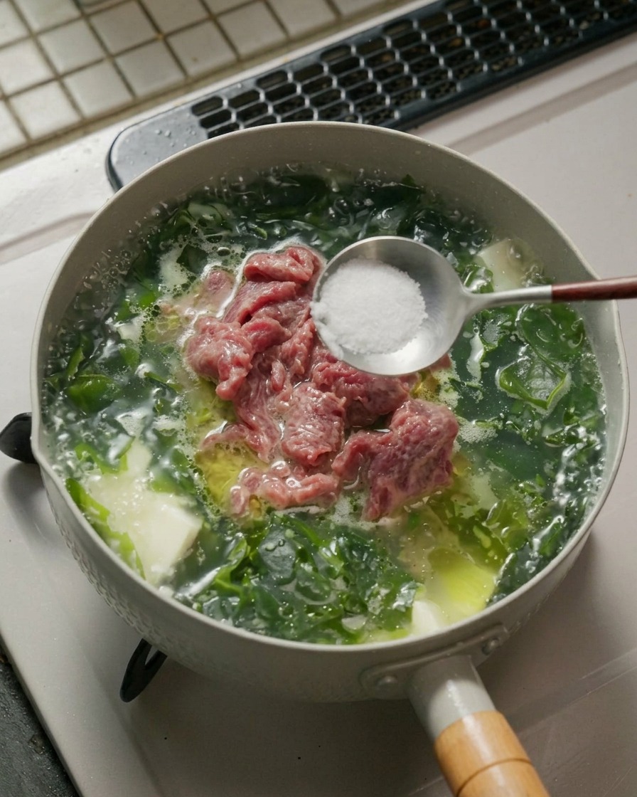 Une cuillère contenant du sel et du poivre blanc au-dessus dune casserole de soupe.