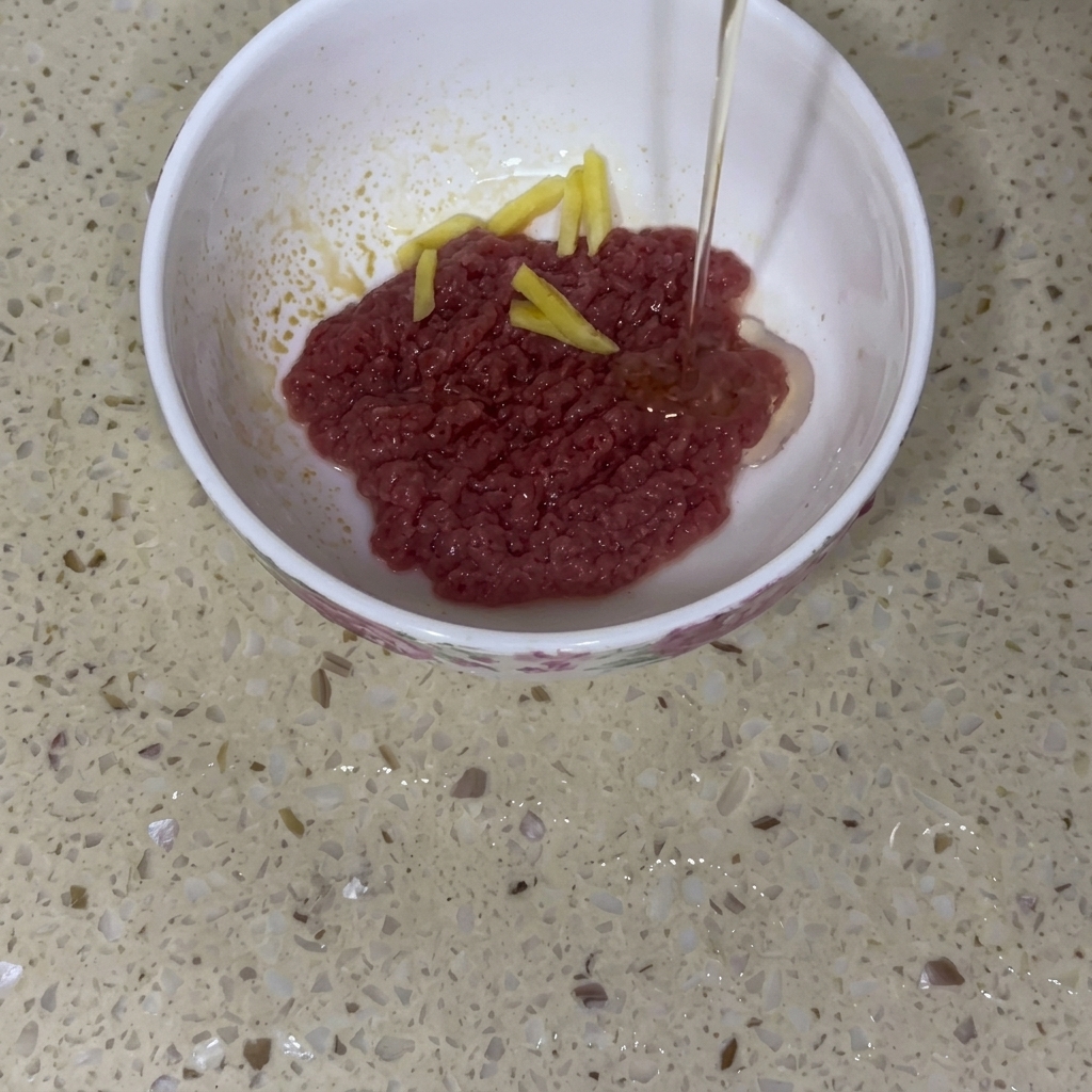 Bœuf haché cru dans un bol en céramique avec du gingembre et un filet dhuile.