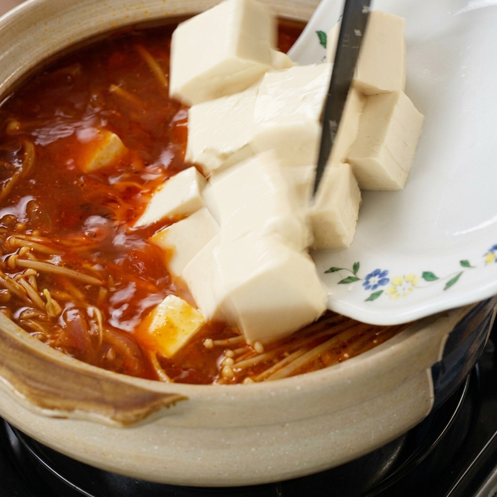 Cubes de tofu glissés dans la soupe avec les champignons enoki.