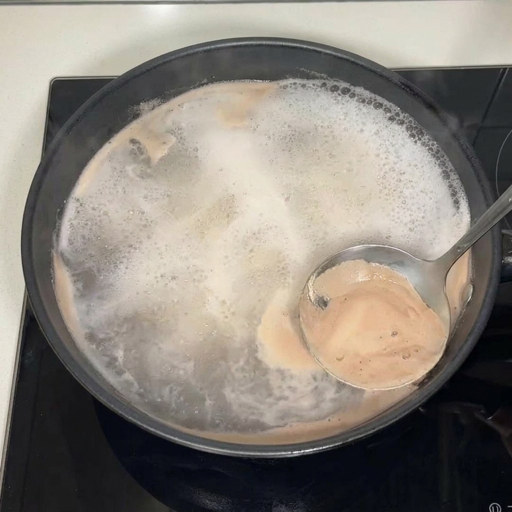 Élimination de lécume à la surface du bouillon avec une louche.