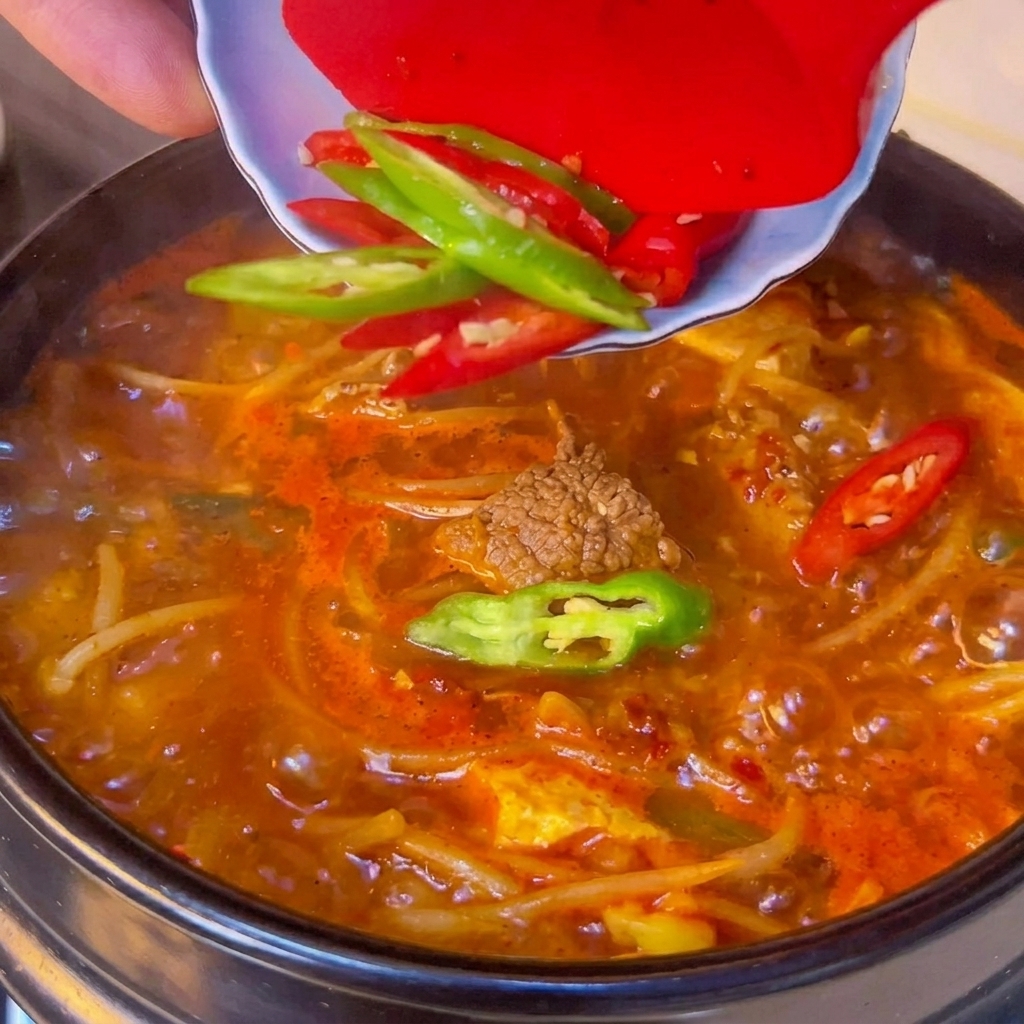Tranches de piments frais ajoutées sur le dessus du ragoût.