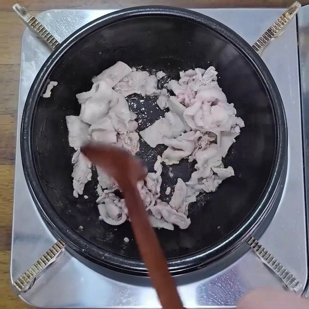 Tranches de porc sautées à la cuillère en bois dans une marmite.