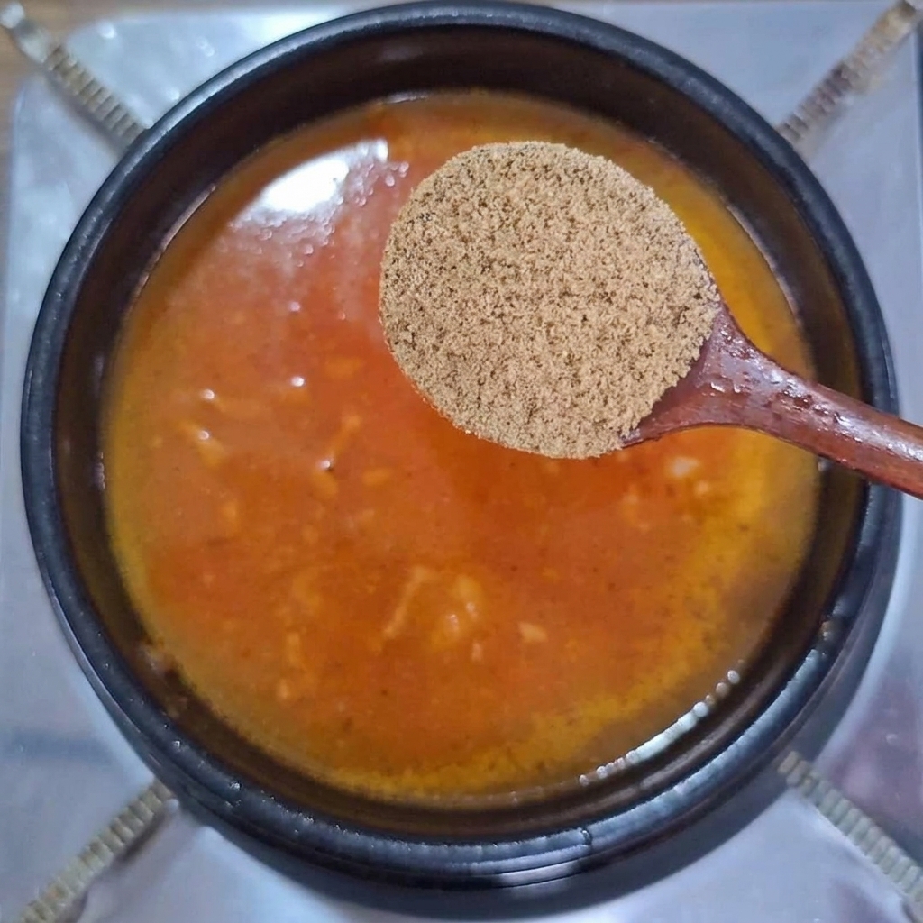 Cuillère en bois avec de la poudre de bouillon de bœuf au-dessus du ragoût.