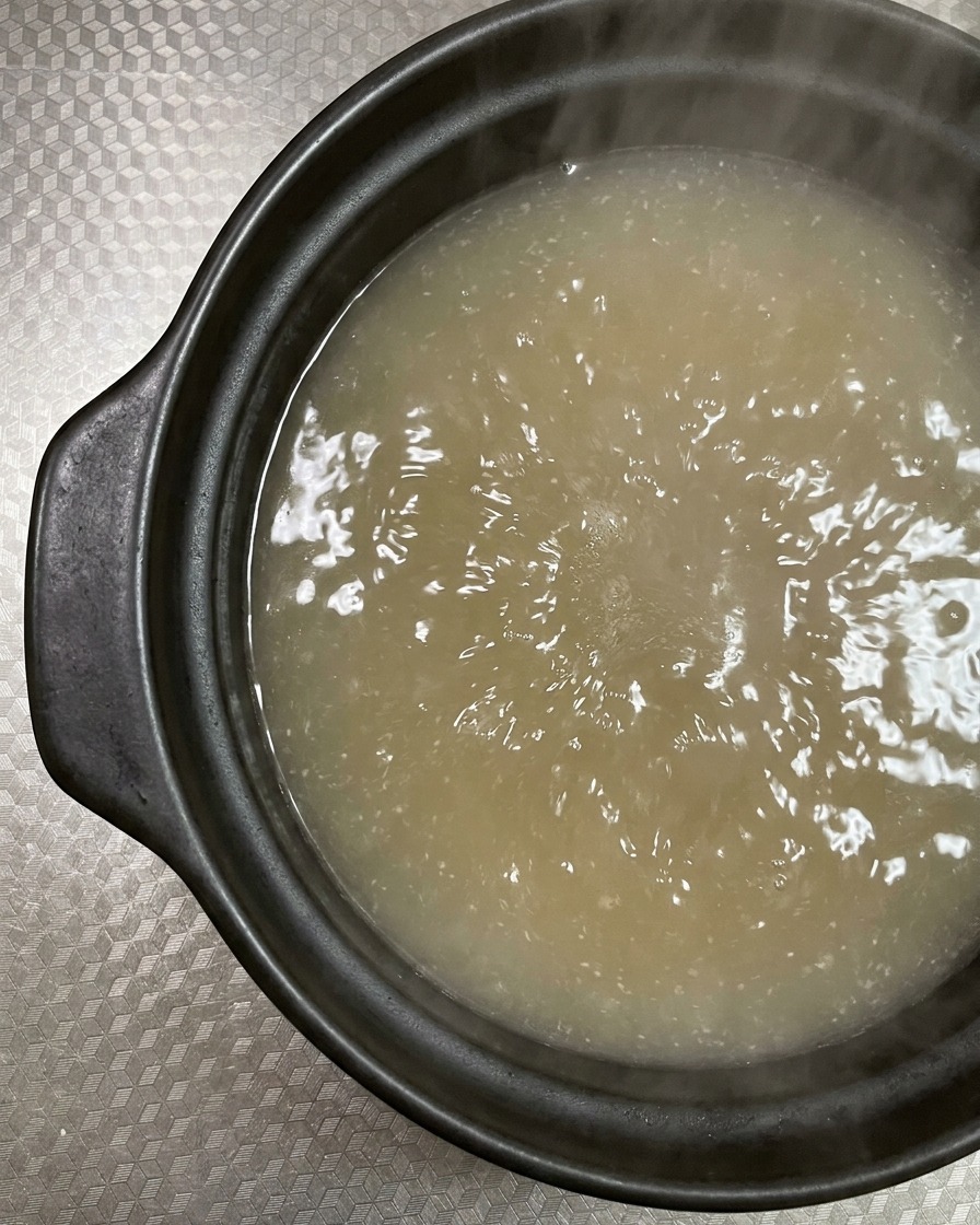 Tranches de poitrine de porc crue et marbrée ajoutées dans un bouillon bouillonnant.