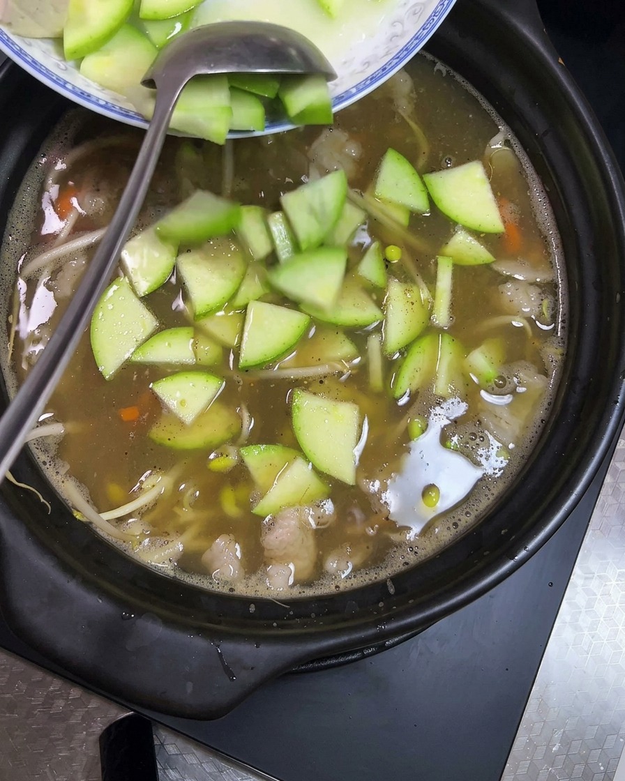 Cubes de tofu et tranches de courgette verte ajoutés dans le pot de terre.