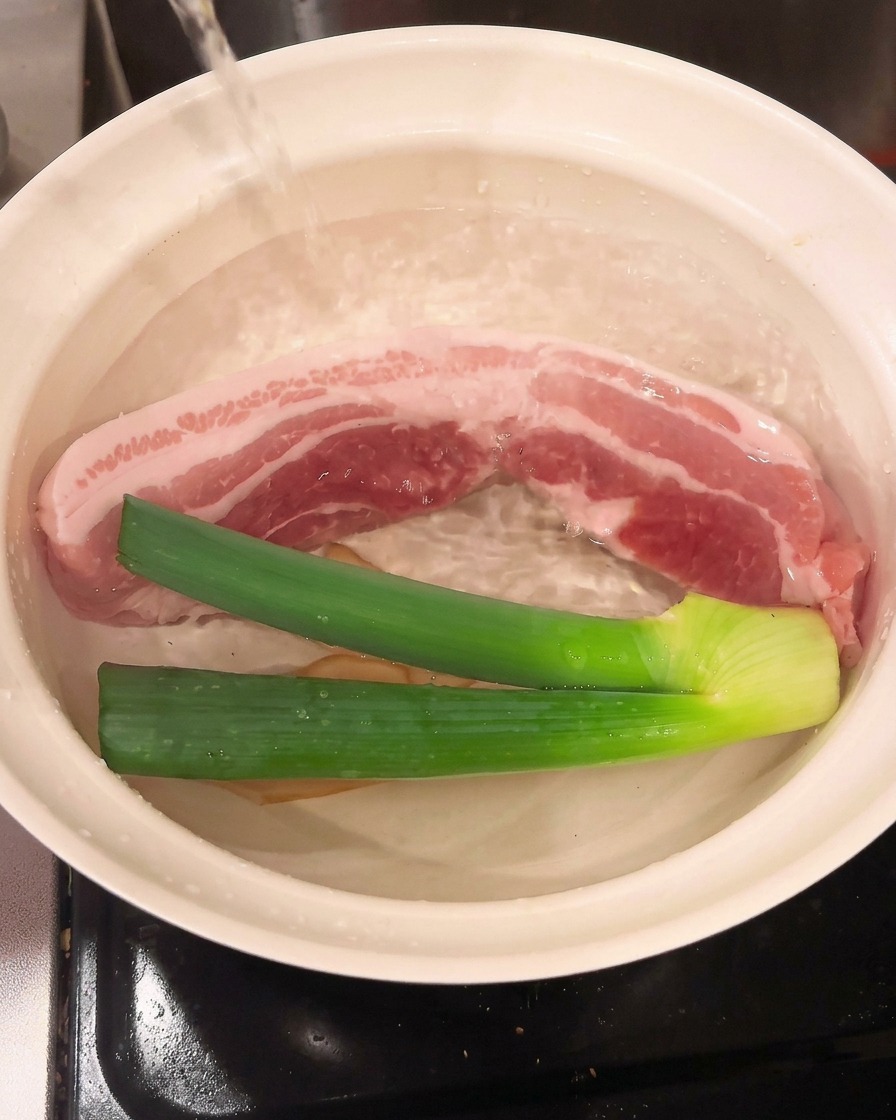 Du vin de cuisine versé dans la casserole contenant le porc et les aromates.