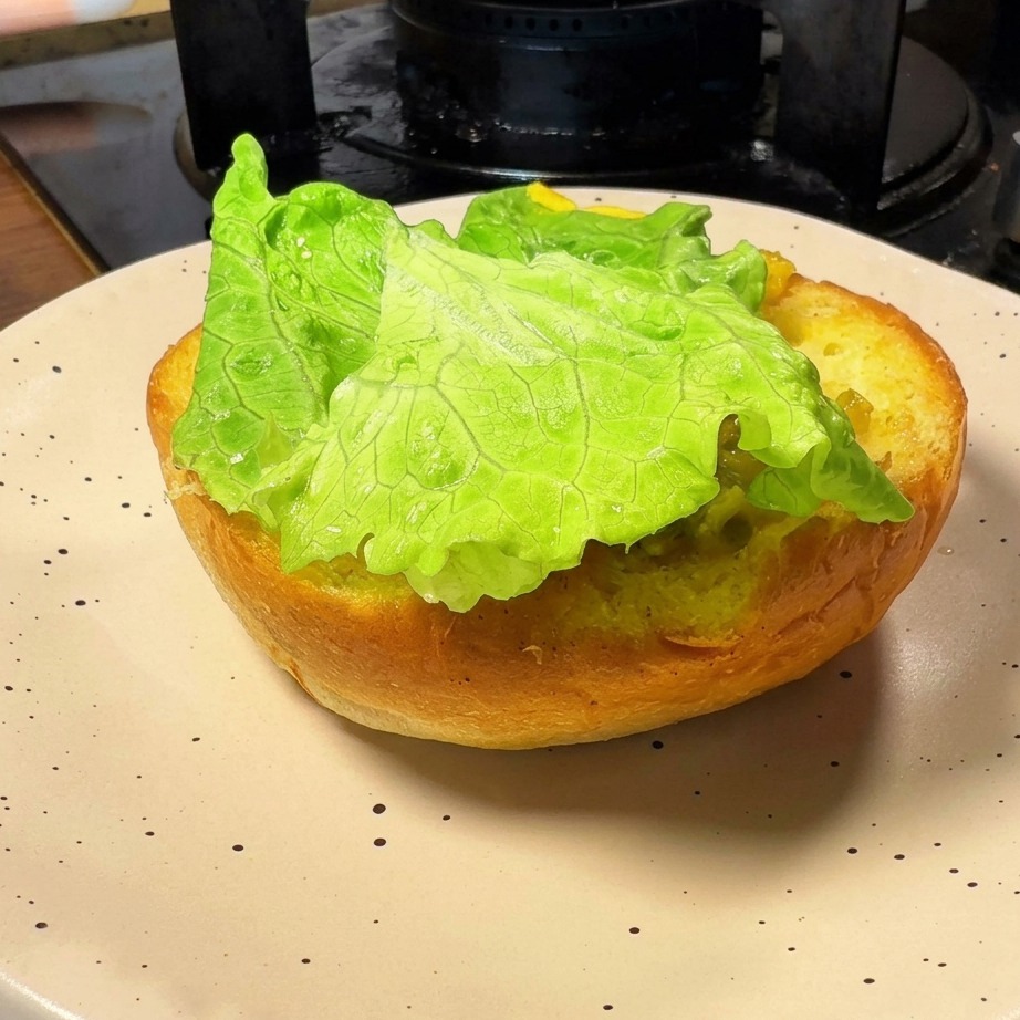 La base dun pain à burger toasté garnie dune feuille de laitue bien verte.